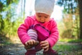 Adorable baby on forest path in nature. Portrait of 1 year old girl in woods with pine cone Royalty Free Stock Photo