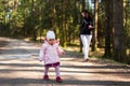Adorable baby on forest path in nature.1 year old girl in woods with her mother