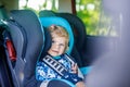 Adorable baby girl with blue eyes sitting in car safety seat. Toddler child going on family vacations and jorney Royalty Free Stock Photo