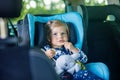 Adorable baby girl with blue eyes sitting in car safety seat. Toddler child going on family vacations and jorney Royalty Free Stock Photo