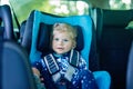 Adorable baby girl with blue eyes sitting in car safety seat. Toddler child going on family vacations and jorney Royalty Free Stock Photo