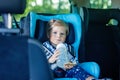 Adorable baby girl with blue eyes sitting in car safety seat. Toddler child going on family vacations and jorney Royalty Free Stock Photo