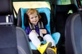 Adorable baby girl with blue eyes sitting in car safety seat. Toddler child going on family vacations and jorney. Happy Royalty Free Stock Photo