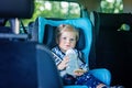 Adorable baby girl with blue eyes sitting in car safety seat. Toddler child going on family vacations and jorney Royalty Free Stock Photo