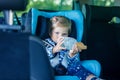 Adorable baby girl with blue eyes sitting in car safety seat. Toddler child going on family vacations and jorney Royalty Free Stock Photo