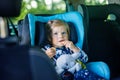 Adorable baby girl with blue eyes sitting in car safety seat. Toddler child going on family vacations and jorney Royalty Free Stock Photo