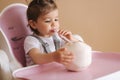 Adorable baby girl drink coconut in high chair. Cute little girl first time taste exotic fruit Royalty Free Stock Photo