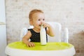 Adorable baby girl drinking milk from bottle sitting in the chair Royalty Free Stock Photo