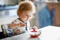 Adorable baby girl eating from spoon fresh healthy raspberries food, child, feeding and development concept. Cute Royalty Free Stock Photo