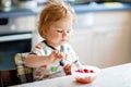 Adorable baby girl eating from spoon fresh healthy raspberries food, child, feeding and development concept. Cute Royalty Free Stock Photo