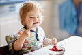 Adorable baby girl eating from spoon fresh healthy raspberries food, child, feeding and development concept. Cute Royalty Free Stock Photo