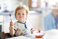 Adorable baby girl eating from spoon fresh healthy raspberries food, child, feeding and development concept. Cute Royalty Free Stock Photo