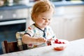 Adorable baby girl eating from spoon fresh healthy raspberries food, child, feeding and development concept. Cute Royalty Free Stock Photo