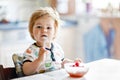 Adorable baby girl eating from spoon fresh healthy raspberries food, child, feeding and development concept. Cute Royalty Free Stock Photo