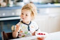 Adorable baby girl eating from spoon fresh healthy raspberries food, child, feeding and development concept. Cute Royalty Free Stock Photo