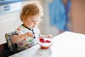 Adorable baby girl eating from spoon fresh healthy raspberries food, child, feeding and development concept. Cute Royalty Free Stock Photo