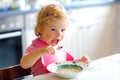 Adorable baby girl eating from spoon vegetable noodle soup. food, child, feeding and development concept. Cute toddler