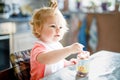 Adorable baby girl eating from spoon vegetables or fruit canned food, child, feeding and development concept. Cute Royalty Free Stock Photo