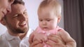 Adorable baby girl in father embrace. Portrait of infant play with mom and dad