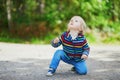 Adorable baby girl in the forest, sitting on the ground and playing with little stones Royalty Free Stock Photo