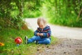 Adorable baby girl in the forest, sitting on the ground and playing with little stones Royalty Free Stock Photo