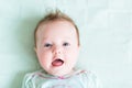 Adorable baby girl on a green knitted blanket smiling Royalty Free Stock Photo