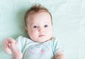 Adorable baby girl on a green knitted blanket smiling Royalty Free Stock Photo