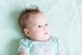 Adorable baby girl in a green shirt on a green knitted blanket smiling Royalty Free Stock Photo