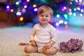 Adorable baby girl holding colorful lights garland in cute hands. Little child in festive clothes decorating Christmas Royalty Free Stock Photo