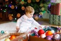 Adorable baby girl holding colorful lights garland in cute hands. Little child in festive clothes decorating Christmas Royalty Free Stock Photo