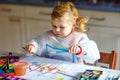 Adorable baby girl learning painting with water colors. Little toddler child drawing at home, during pandemic Royalty Free Stock Photo