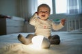 Adorable baby girl playing with bedside lamp in nursery Royalty Free Stock Photo