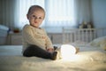 Adorable baby girl playing with bedside lamp in nursery Royalty Free Stock Photo
