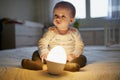 Adorable baby girl playing with bedside lamp in nursery Royalty Free Stock Photo