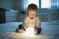 Adorable baby girl playing with bedside lamp in nursery Royalty Free Stock Photo