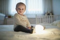 Adorable baby girl playing with bedside lamp in nursery Royalty Free Stock Photo