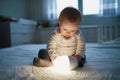 Adorable baby girl playing with bedside lamp in nursery Royalty Free Stock Photo