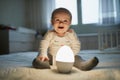 Adorable baby girl playing with bedside lamp in nursery Royalty Free Stock Photo