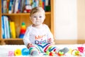 Adorable baby girl playing with educational toys in nursery. Happy healthy child having fun with colorful different toys Royalty Free Stock Photo