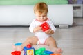 Adorable Baby Girl Playing With Educational Toys In Nursery. Happy Healthy Child Having Fun With Colorful Different Toys