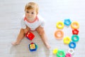 Adorable baby girl playing with educational toys in nursery. Happy healthy child having fun with colorful different toys Royalty Free Stock Photo