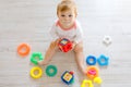 Adorable baby girl playing with educational toys in nursery. Happy healthy child having fun with colorful different toys Royalty Free Stock Photo