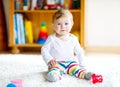 Adorable baby girl playing with educational toys in nursery. Happy healthy child having fun with colorful different toys Royalty Free Stock Photo