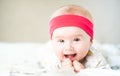 Adorable baby girl with red head band looking towards camera and smiling. Health concept