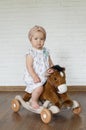 Adorable baby girl riding toy horse. Kid play indoor. Baby rocking