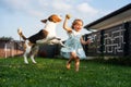 Adorable baby girl runs together with beagle dog in backyard on summer day Royalty Free Stock Photo