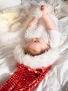 Adorable baby girl in Santa hat lying on the bed and playing Royalty Free Stock Photo