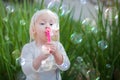 Adorable Baby Girl Sitting On Bench Having Fun Blowing Bubbles Royalty Free Stock Photo