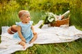 Adorable baby girl sitting on blanket at the park with basket and flowers, parents with beautiful toddler having a Royalty Free Stock Photo