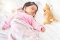 Adorable baby girl sleeping peacefully in her bed with stuffed animal toy. Baby lying fast asleep on white bed with Royalty Free Stock Photo